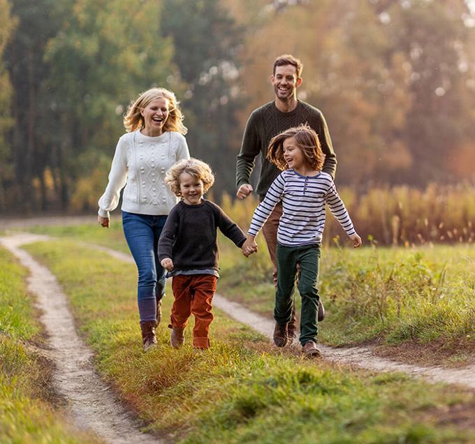 family unit walking along path in field