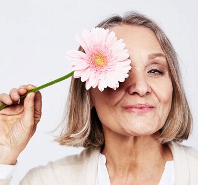 older lady holding flower in front of face